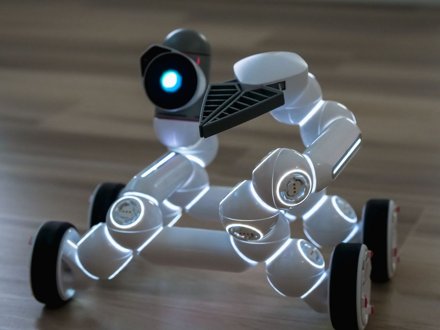 Robot blanco con ruedas, cámara luminosa y piezas articuladas